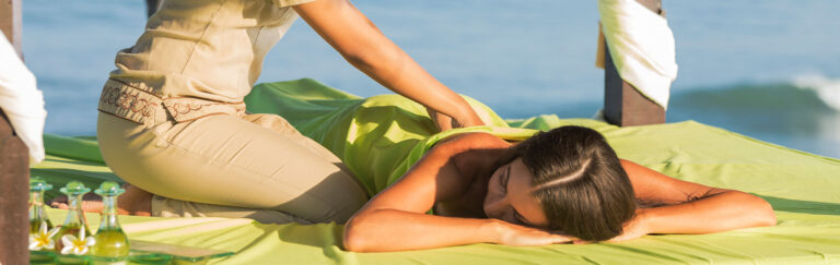 Mulher recebe massagem na praia.