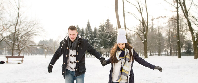 Casal com roupas cálidas anda arduamente pela neve.