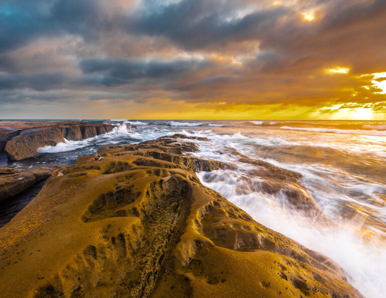 Mar quebra em rochas com erodidas pelas ondas diante do céu nublado na Califórnia.