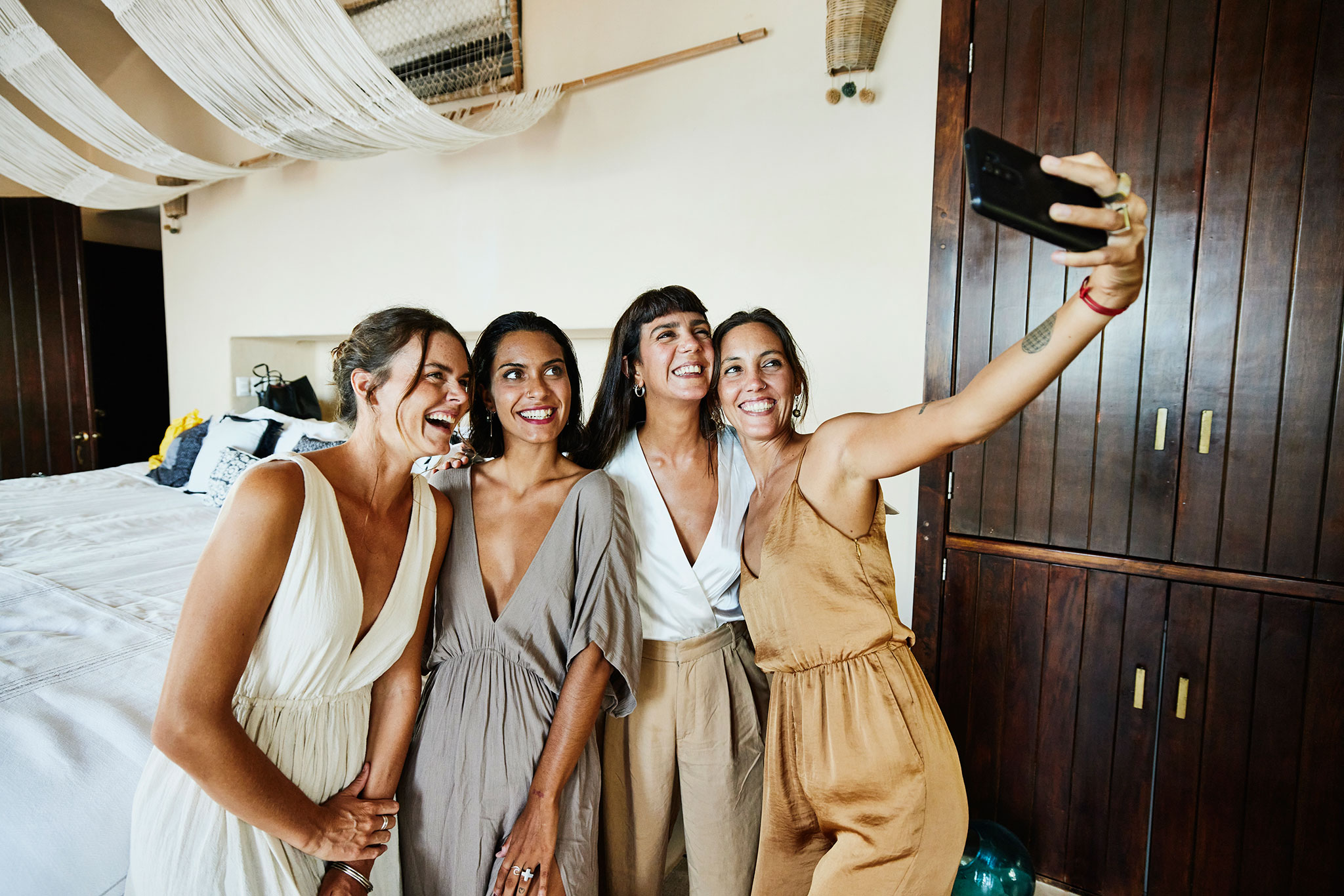 Quatro amigas posam para uma selfie em uma luxuosa suíte antes de um casamento.
