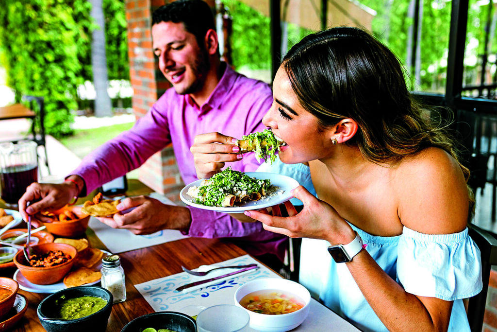 Jovem latina feliz comendo tacos mexicanos em um terraço de restaurante no México, América latina, em um dia de verão